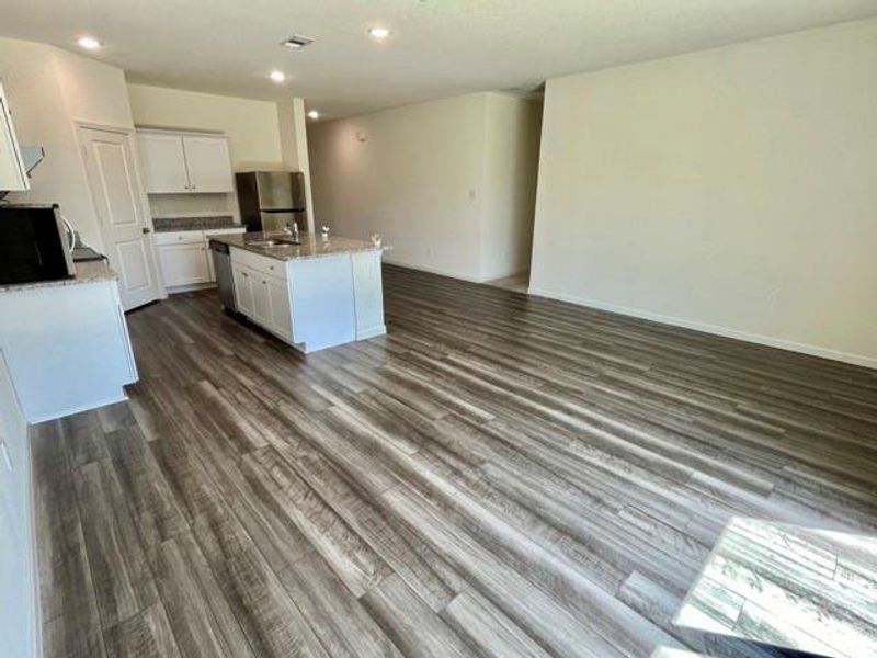 Kitchen with appliances with stainless steel finishes, dark hardwood / wood-style floors, a center island with sink, and white cabinetry