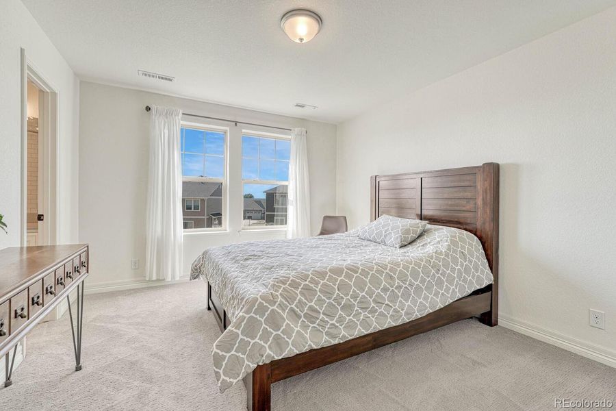 This guest room features a comfortable and inviting space with ample natural light and includes its own full bath for added convenience and privacy.