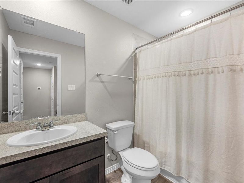 The secondary bath features tile flooring, dark stained cabinetry and light countertops and a shower/tub combo. Perfect for accommodating any visiting family and friends.