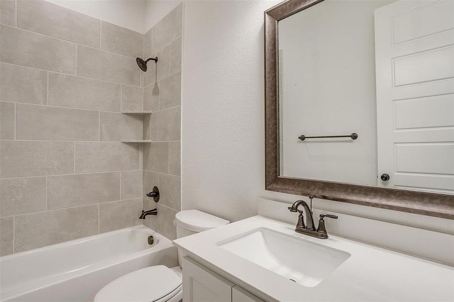 Full bathroom featuring vanity, tiled shower / bath combo, and toilet