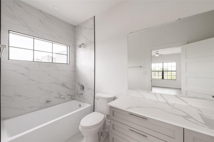 *Representative Photo. Primary bathroom featuring marble- like tiles, a built-in bathtub, sleek vanity with ample storage, and a window for natural light.