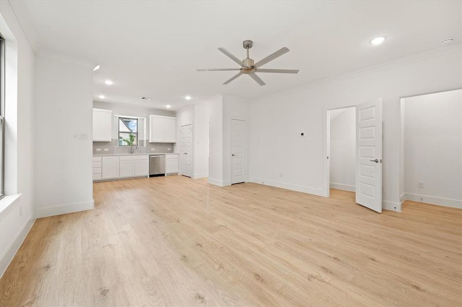 Unfurnished living room featuring light hardwood / wood-style floors, sink, ornamental molding, and ceiling fan