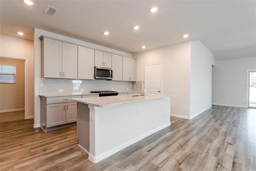 Kitchen featuring sink, luxury vinyl flooring, and a kitchen island with sink