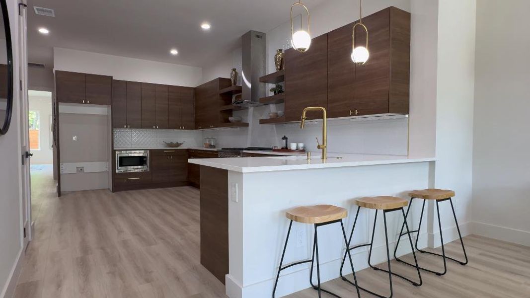 Kitchen featuring kitchen peninsula, light hardwood / wood-style flooring, decorative backsplash, and dark brown cabinetry