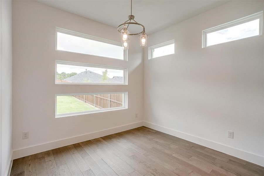 Unfurnished room featuring a notable chandelier, hardwood / wood-style floors, and a wealth of natural light