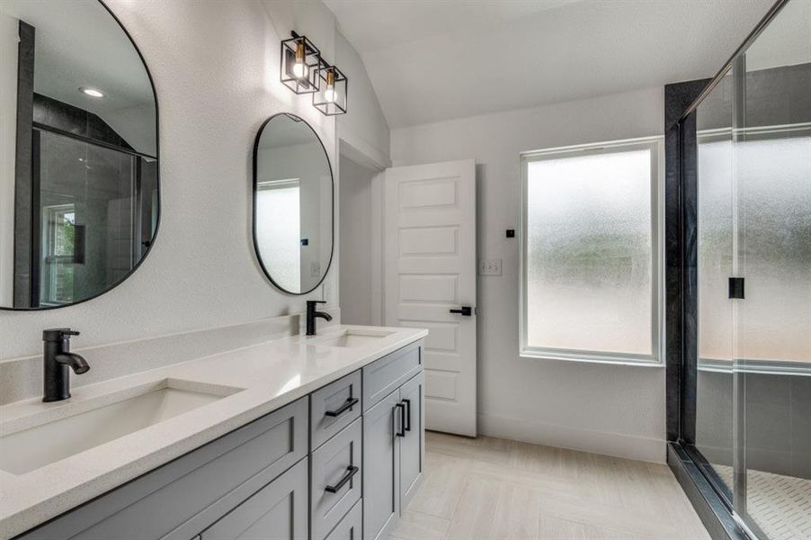 Bathroom with a shower with door, vanity, and vaulted ceiling