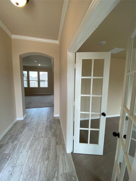 Corridor featuring light carpet, crown molding, and french doors