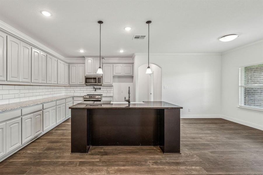 Kitchen with stainless steel appliances, sink, decorative backsplash, light stone countertops, and dark hardwood / wood-style flooring