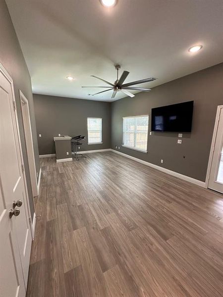 Unfurnished living room featuring dark wood-type flooring and ceiling fan