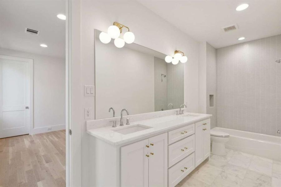 Full bathroom featuring hardwood / wood-style floors, tiled shower / bath, vanity, and toilet