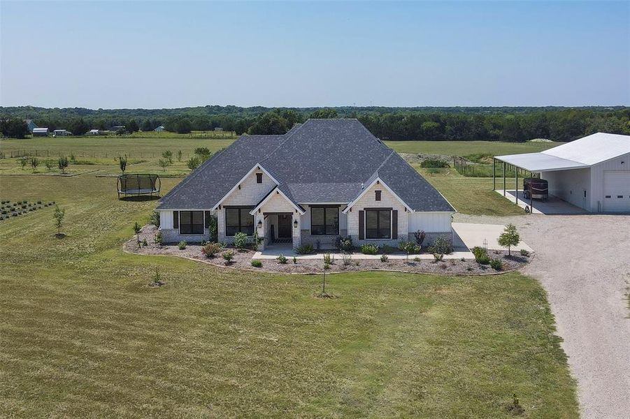 View of front of house featuring a front yard, a rural view, a garage, and a porch