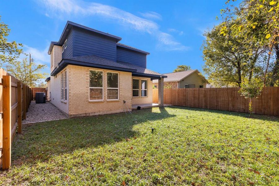 Rear view of property featuring a yard and central AC