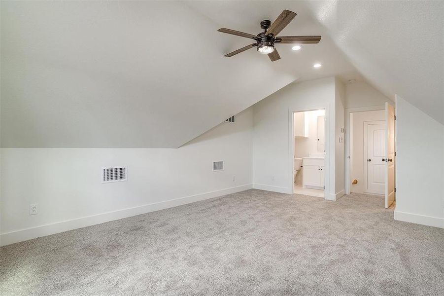 Bonus room with light colored carpet, lofted ceiling, and ceiling fan and full bathroom