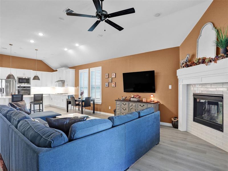 Spacious living room with gas fireplace and plantation shutters leading to a covered patio and backyard.