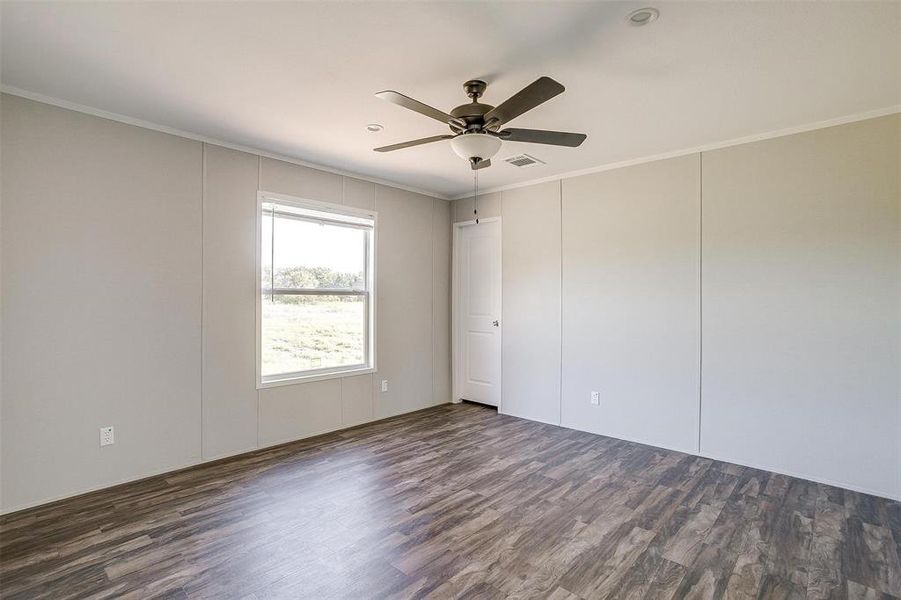 Unfurnished room featuring dark wood-type flooring, ceiling fan, and ornamental molding