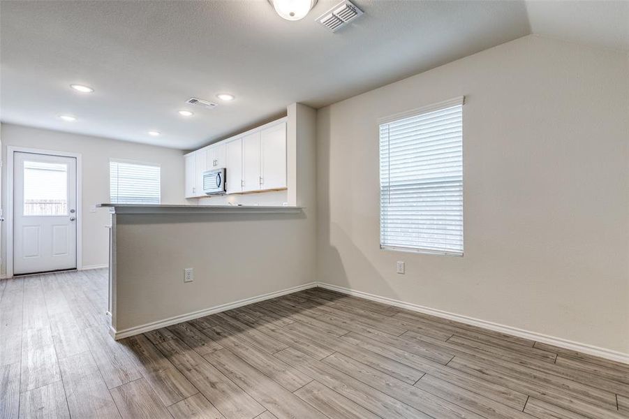 Empty room with light hardwood / wood-style flooring and vaulted ceiling