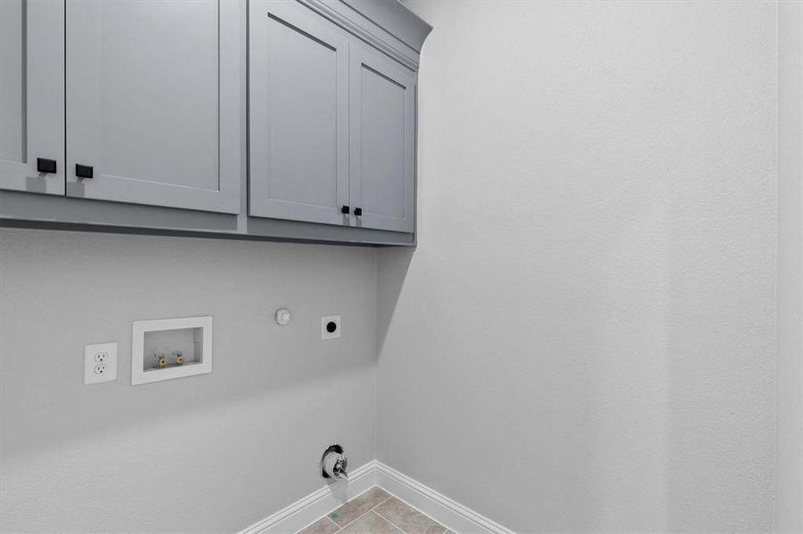 Washroom with cabinets, washer hookup, light tile patterned floors, electric dryer hookup, and hookup for a gas dryer