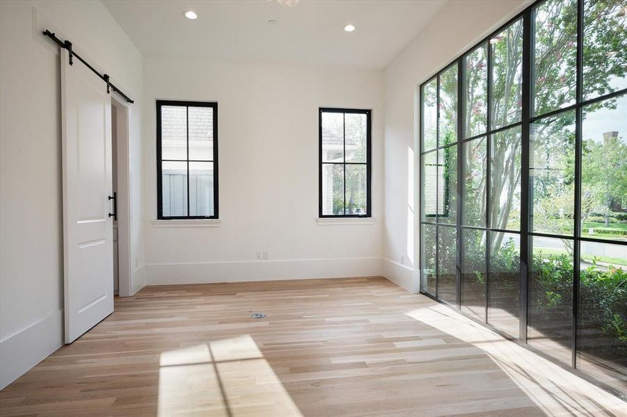 Spare room with a barn door and light hardwood / wood-style floors