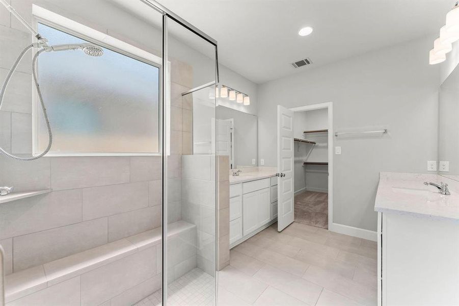 Double doors lead to the primary bath with two vanities, a large corner glass-enclosed shower and large walk-in closet.