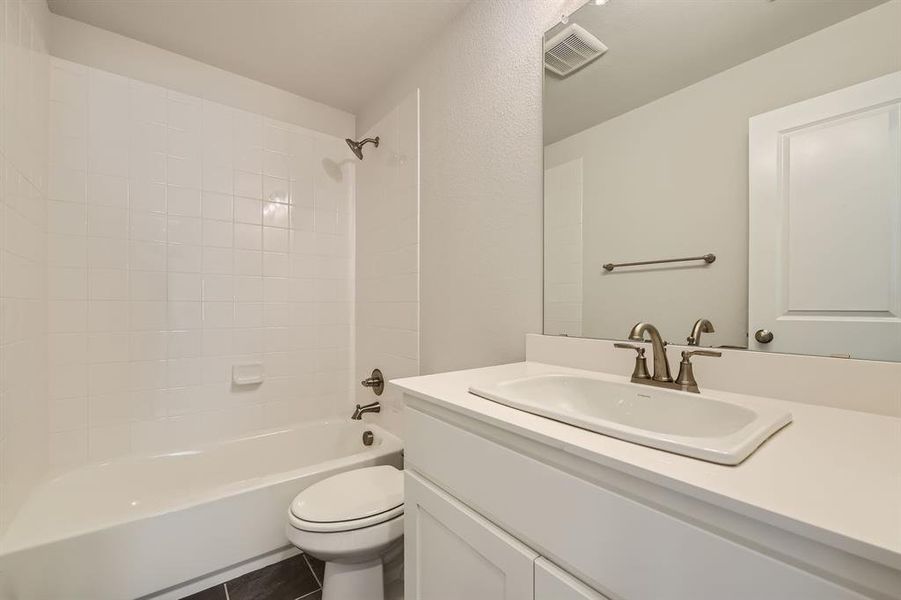 Full bathroom featuring tiled shower / bath, vanity, toilet, and tile patterned floors