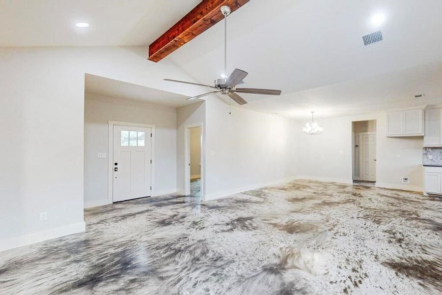 Unfurnished living room featuring vaulted ceiling with beams and ceiling fan with notable chandelier