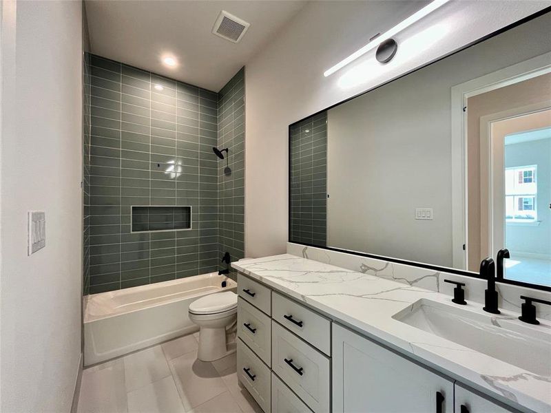 Full bathroom with tile patterned floors, vanity, toilet, and tiled shower / bath