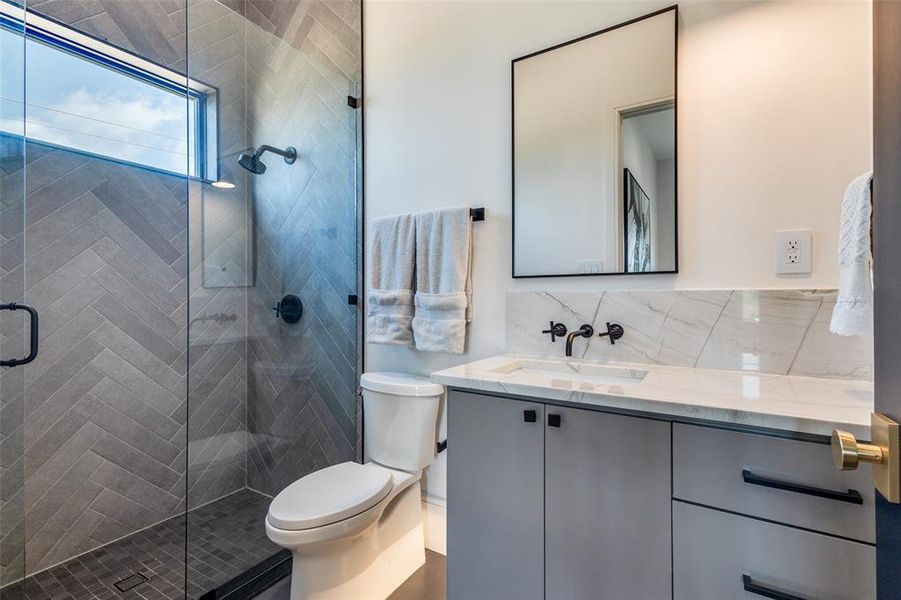 Bathroom with a shower with shower door, backsplash, oversized vanity, and toilet