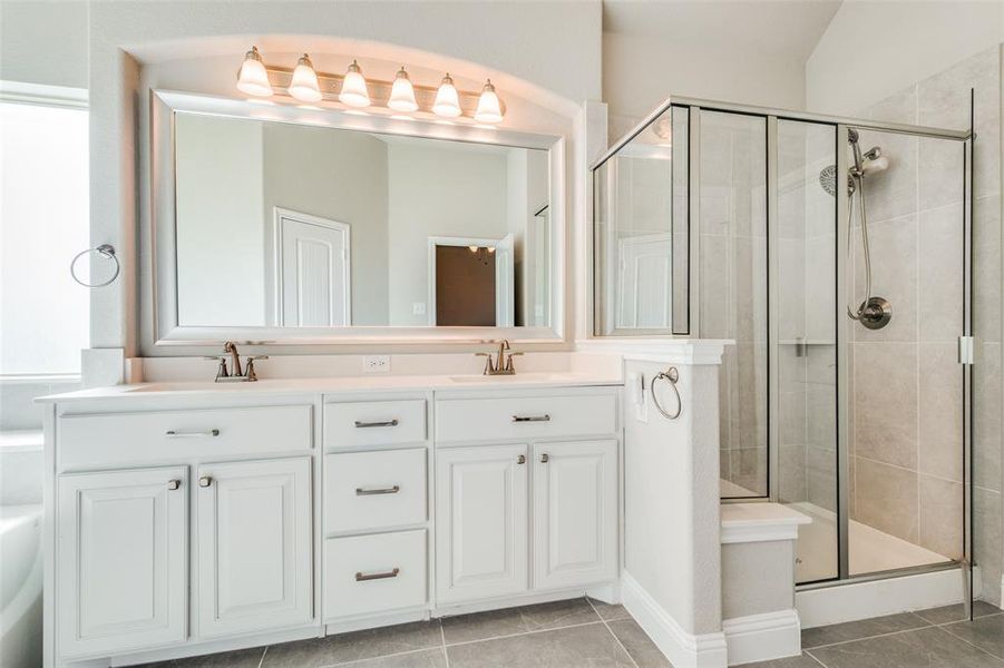 Bathroom with a shower with shower door, tile patterned floors, vaulted ceiling, and double vanity