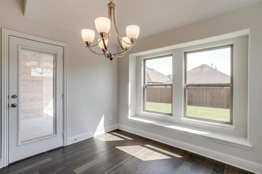 Unfurnished dining area with a notable chandelier, plenty of natural light, and dark hardwood / wood-style flooring