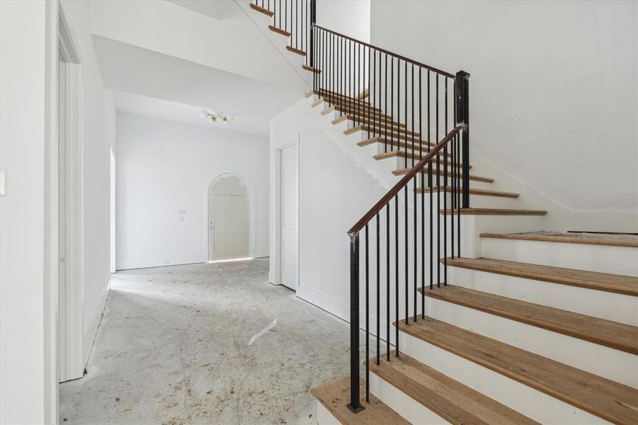 View toward the entry.  The study is the door to the left in this picture.  Storage under the stairs to the right and more storage in the second door on the left.  Bespoke staircase with fitted iron bannister and railing leading to the unique and ingenious layout of the second floor - private, secluded game room to the right or bedrooms to the left. Photo as of 9/3/2024