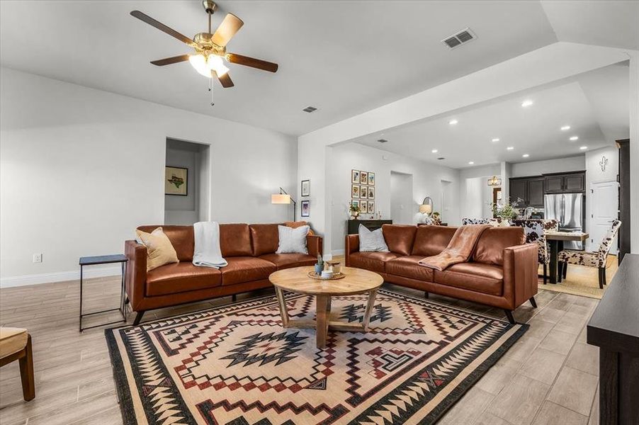 Living room with ceiling fan, vaulted ceiling, and light wood-type flooring