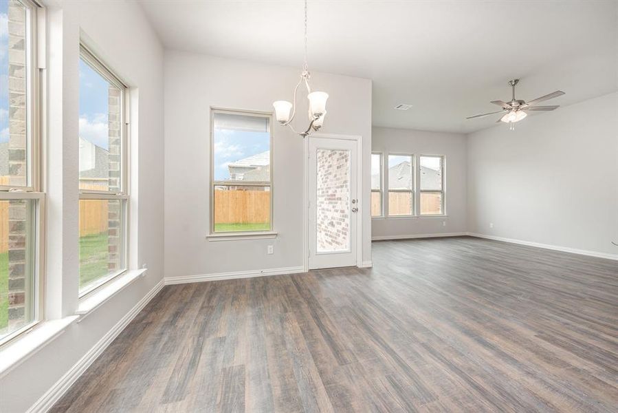 Unfurnished dining area with ceiling fan with notable chandelier, dark hardwood / wood-style flooring, and a healthy amount of sunlight