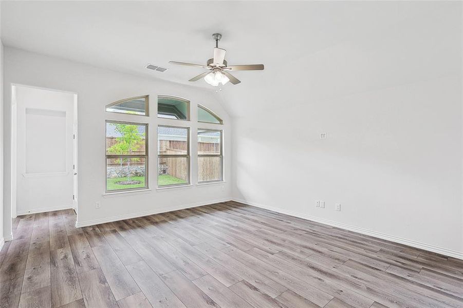 Empty room with light hardwood / wood-style flooring, lofted ceiling, and ceiling fan