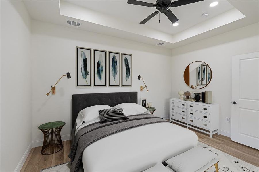 Bedroom with ceiling fan, light hardwood / wood-style flooring, and a tray ceiling