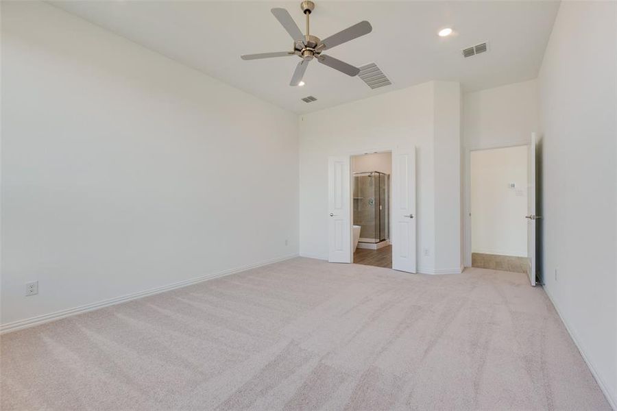 Unfurnished bedroom featuring light carpet, ensuite bath, and ceiling fan