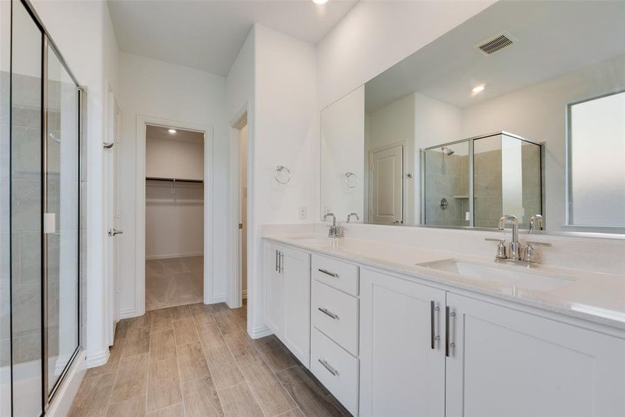 Bathroom featuring a shower with shower door and dual bowl vanity