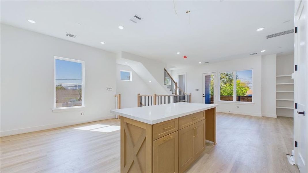 Alternate view of the living and dining areas from the kitchen angle, showcasing the open layout. The kitchen island includes a perfect spot for a wine cooler, adding both convenience and style.