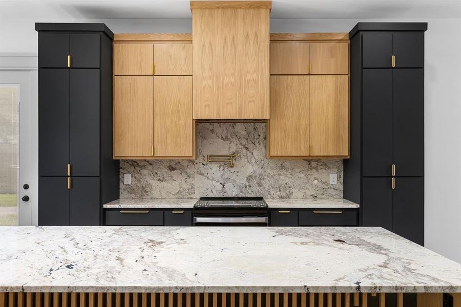 Kitchen with light stone countertops, a center island, stainless steel electric range oven, and backsplash