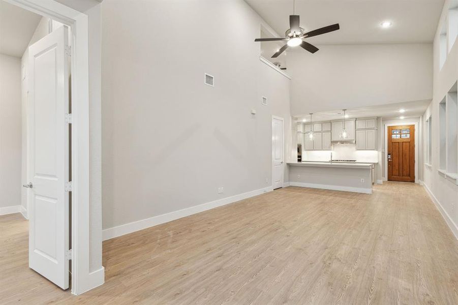 Unfurnished living room with high vaulted ceiling, ceiling fan, and light hardwood / wood-style floors