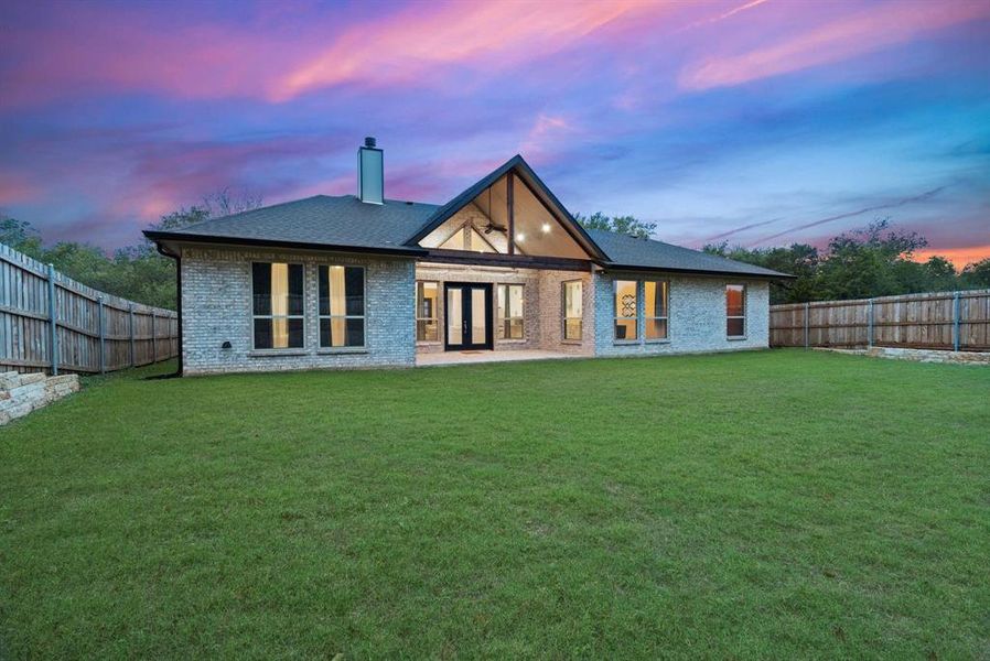 Back house at dusk with a yard