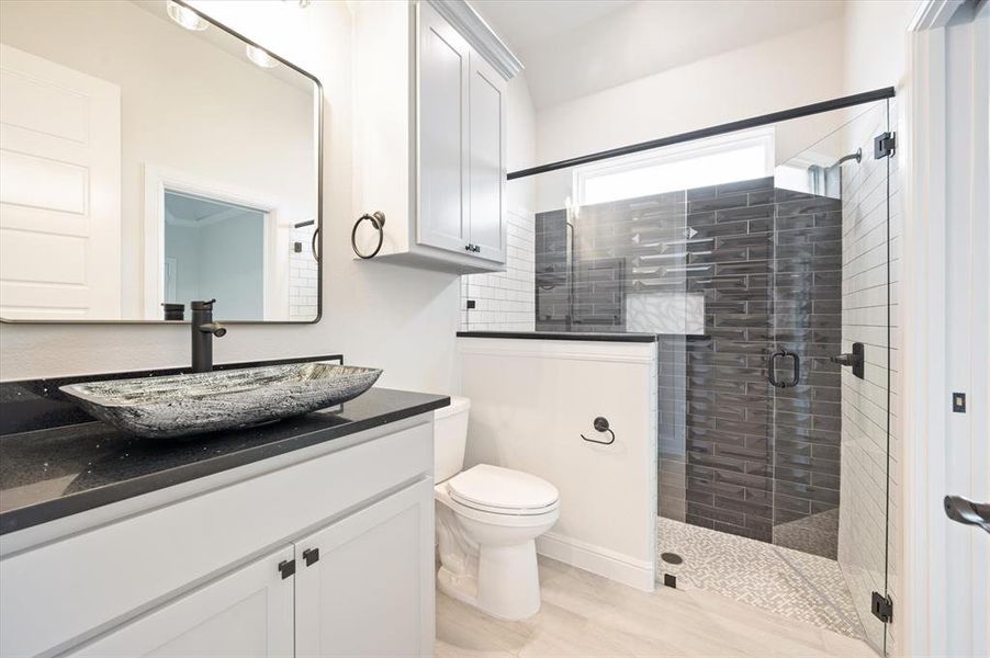 Bathroom featuring a shower with shower door, toilet, and vanity