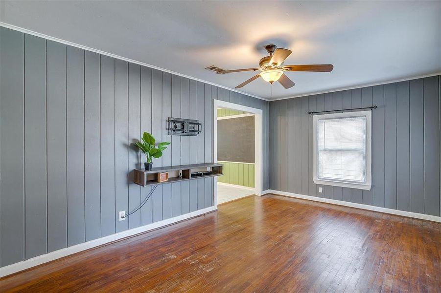 Spare room featuring crown molding, hardwood / wood-style flooring, wooden walls, and ceiling fan