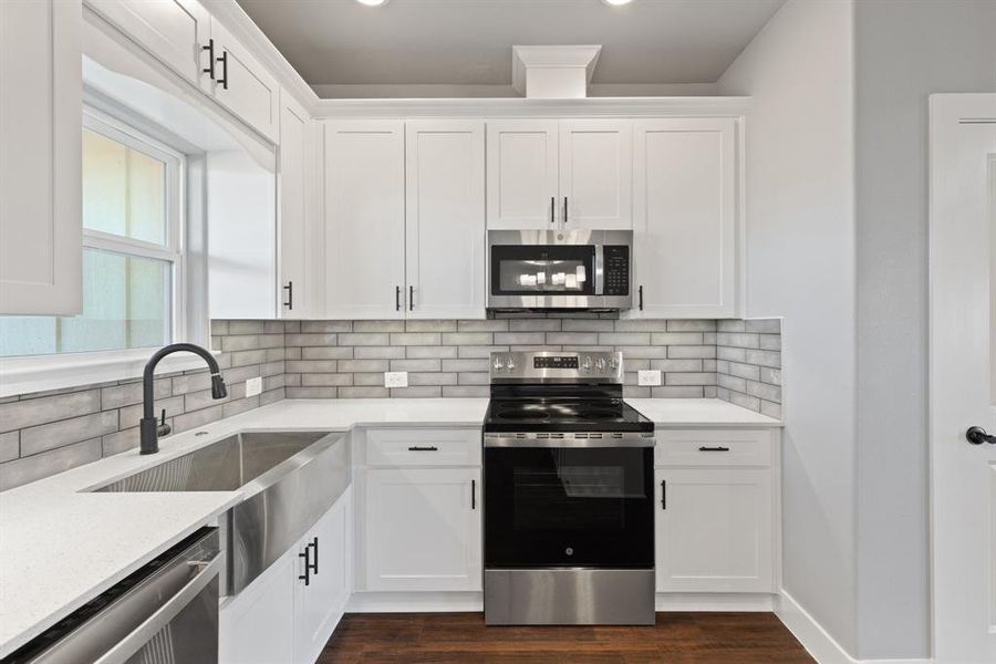 Kitchen with white cabinets, backsplash, and stainless steel appliances