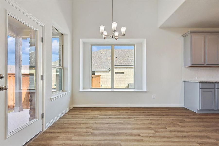 Unfurnished dining area with a chandelier, light hardwood / wood-style flooring, and plenty of natural light