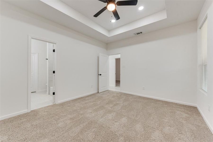 Carpeted empty room with a tray ceiling and ceiling fan