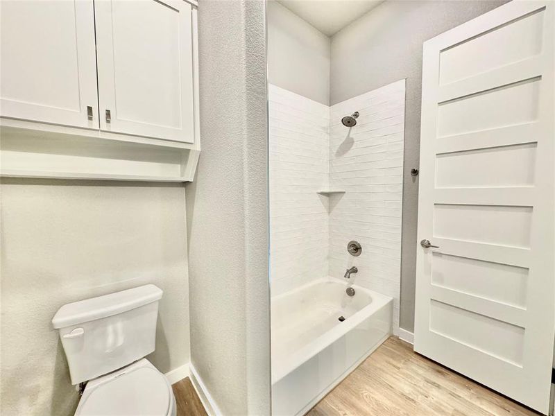 Bathroom with wood-type flooring, toilet, and tiled shower / bath