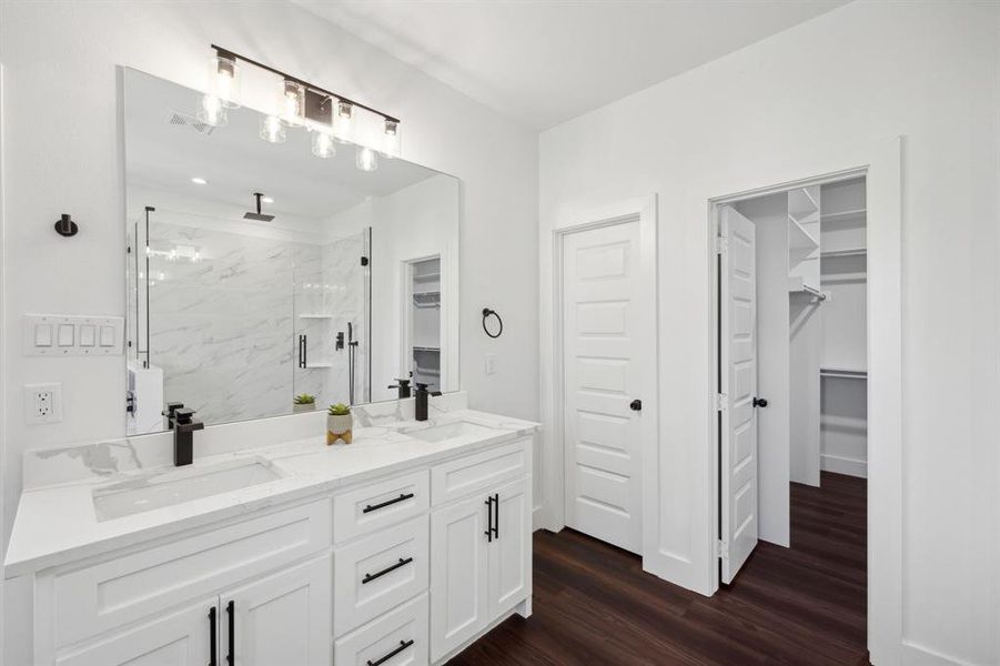 Bathroom with a shower with door, wood-type flooring, and double sink vanity