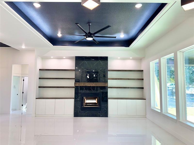 Unfurnished living room with a fireplace, a tray ceiling, and plenty of natural light