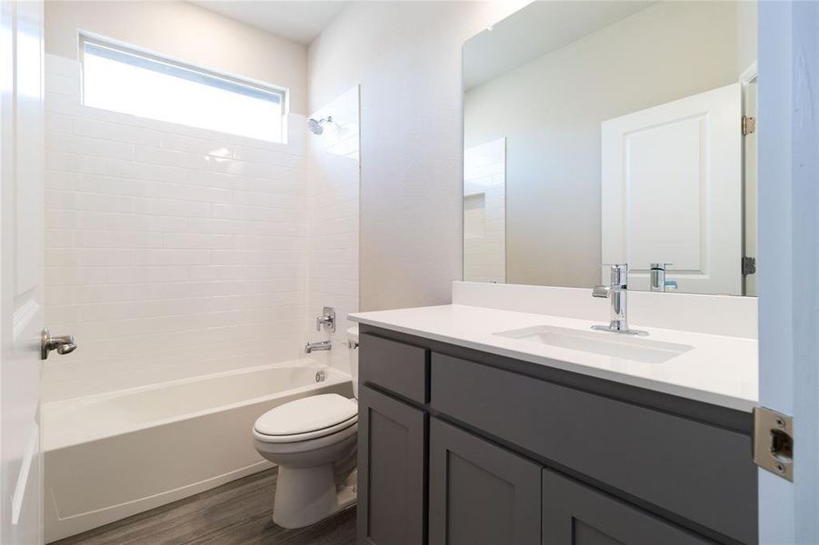 Full bathroom with toilet, tiled shower / bath combo, vanity, and hardwood / wood-style flooring