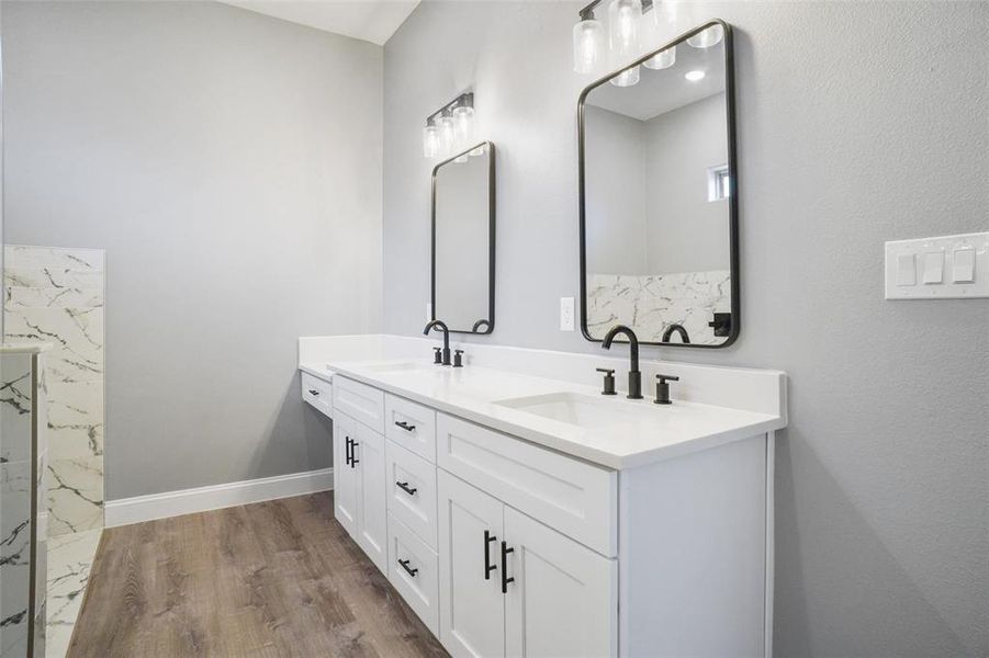 Bathroom with dual vanity and wood-type flooring